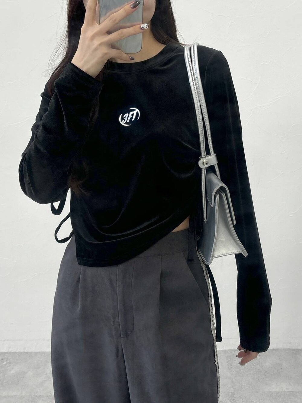 シルバー系のショルダーバッグ、グレー系のスラックス、ブラック系のTシャツ/カットソーを着用したレディースの冬コーディネートの3枚目の写真