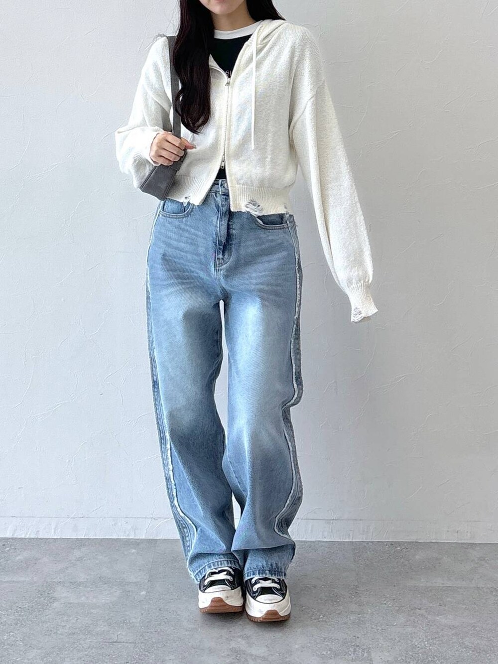 ブラック系のトートバッグ、ブラック系のTシャツ/カットソー、ブルー系のデニムパンツを着用したレディースの秋コーディネートの2枚目の写真