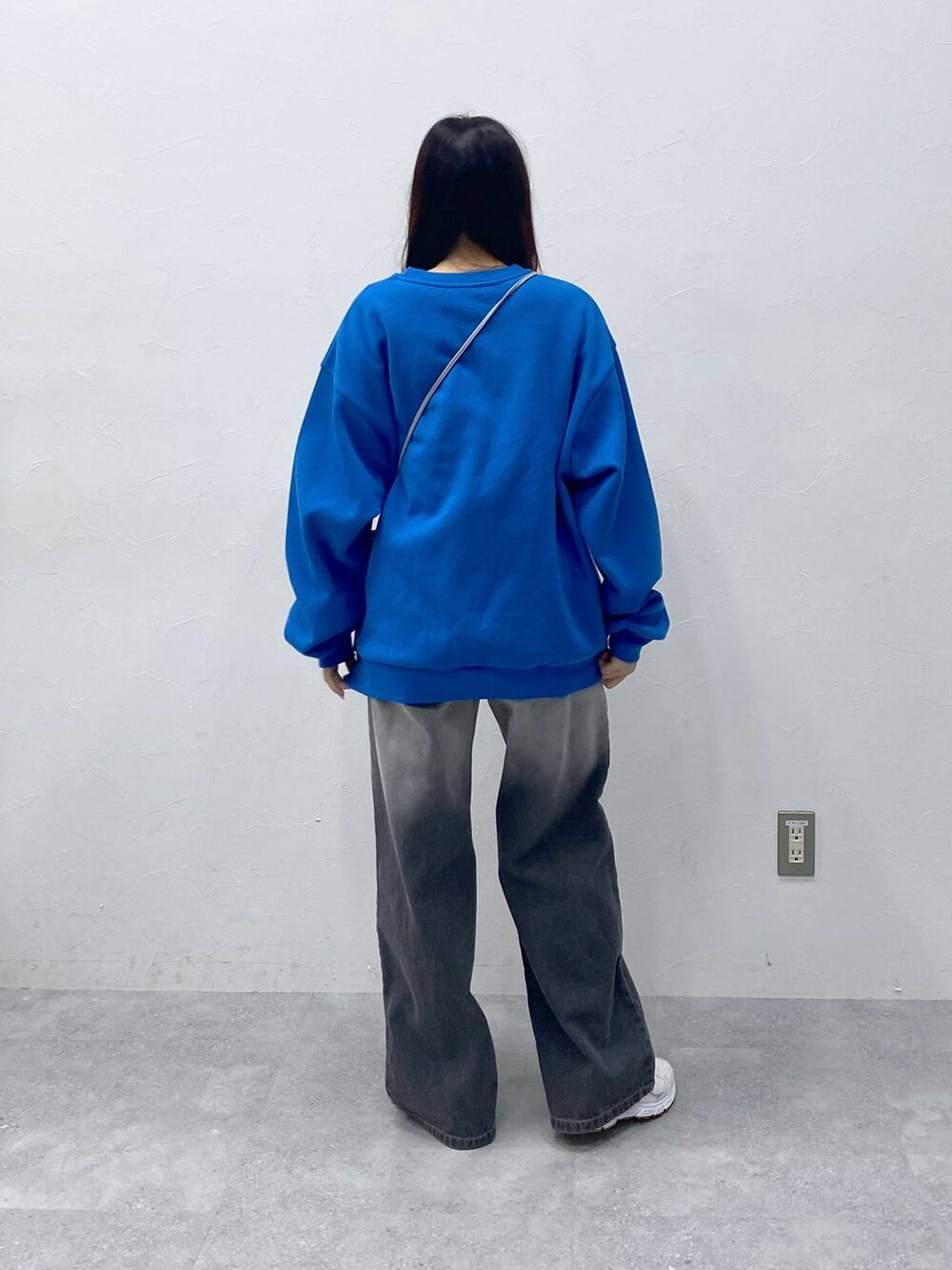 グレー系のショルダーバッグ、ブラック系のデニムパンツ、ブルー系のスウェットを着用したレディースの冬コーディネートの5枚目の写真