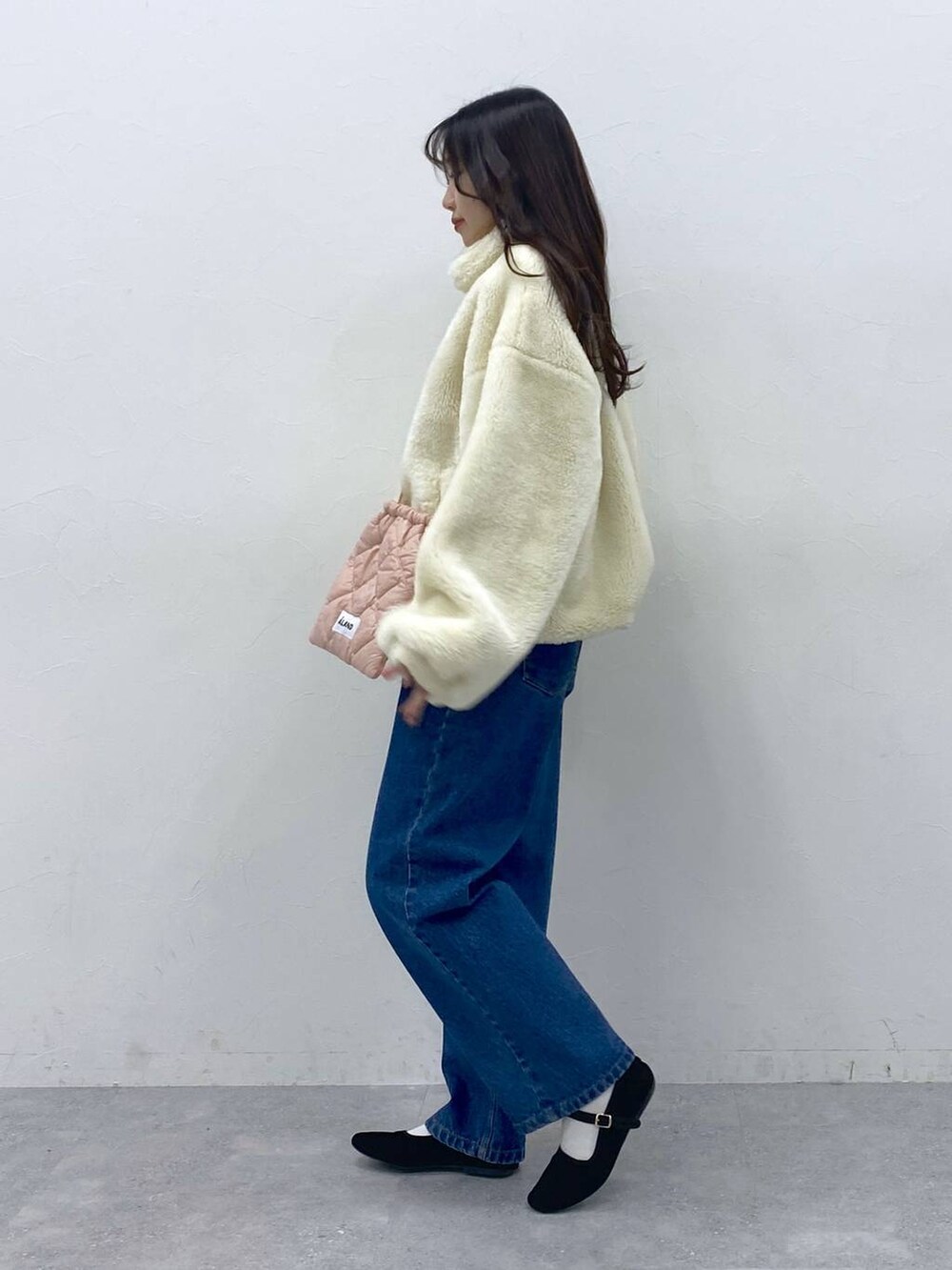 ブラック系のパンプス、ピンク系のショルダーバッグ、ブルー系のデニムパンツを着用したレディースの冬コーディネートの3枚目の写真