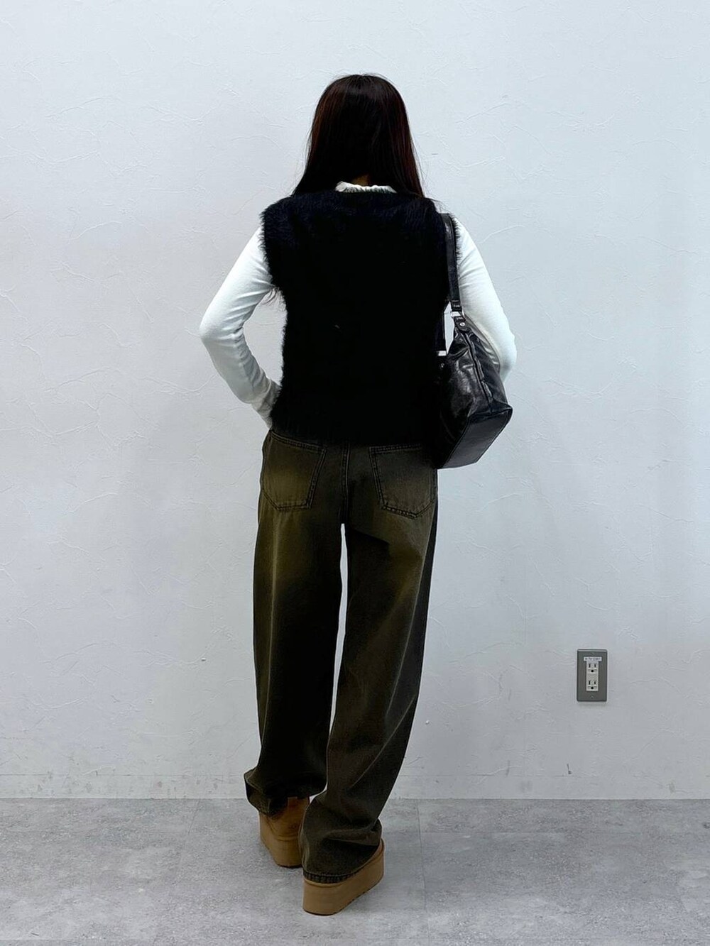 ブラック系のデニムパンツ、ブラック系のベスト、ブラック系のハンドバッグを着用したレディースの秋コーディネートの4枚目の写真