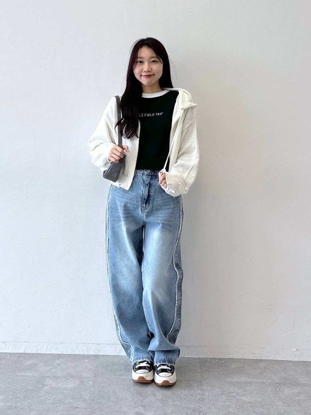 ブラック系のトートバッグ、ブラック系のTシャツ/カットソー、ブルー系のデニムパンツを着用したレディースの秋コーディネートの3枚目の写真