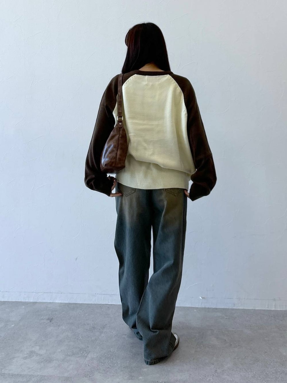 ブラウン系のニット/セーター、ブルー系のデニムパンツ、ブラウン系のハンドバッグを着用したレディースの冬コーディネートの5枚目の写真