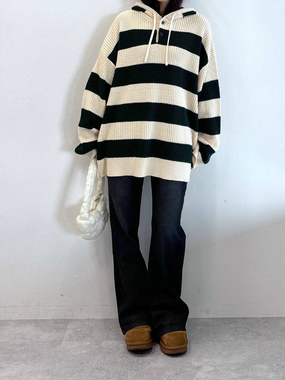 ホワイト系のショルダーバッグ、ブラック系のデニムパンツ、グリーン系のニット/セーターを着用したレディースの冬コーディネートの2枚目の写真