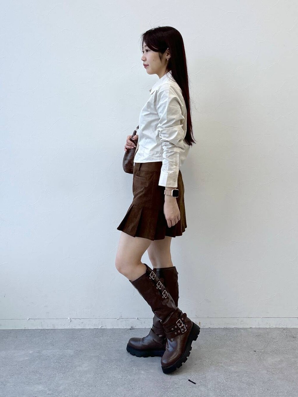 ブラウン系のブーツ、ブラウン系のスカート、ブラウン系のハンドバッグを着用したレディースの冬コーディネートの3枚目の写真