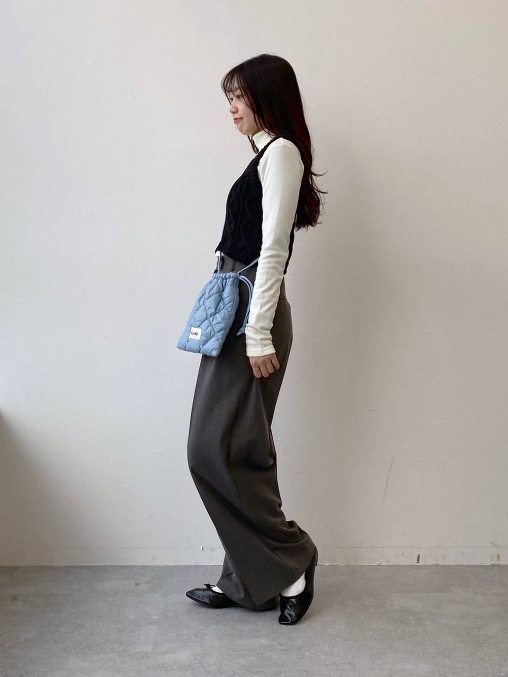 ブラック系のバレエシューズ、ブルー系のショルダーバッグ、グレー系のスラックスを着用したレディースの冬コーディネートの3枚目の写真