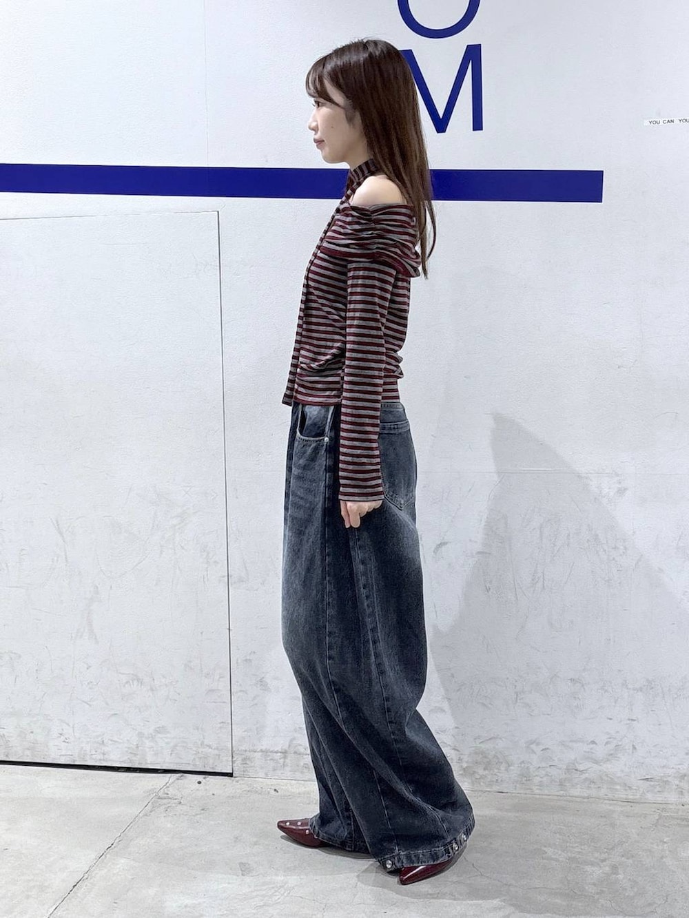 レッド系のTシャツ/カットソー、ブルー系のデニムパンツ、レッド系のサンダルを着用したレディースの秋コーディネートの3枚目の写真