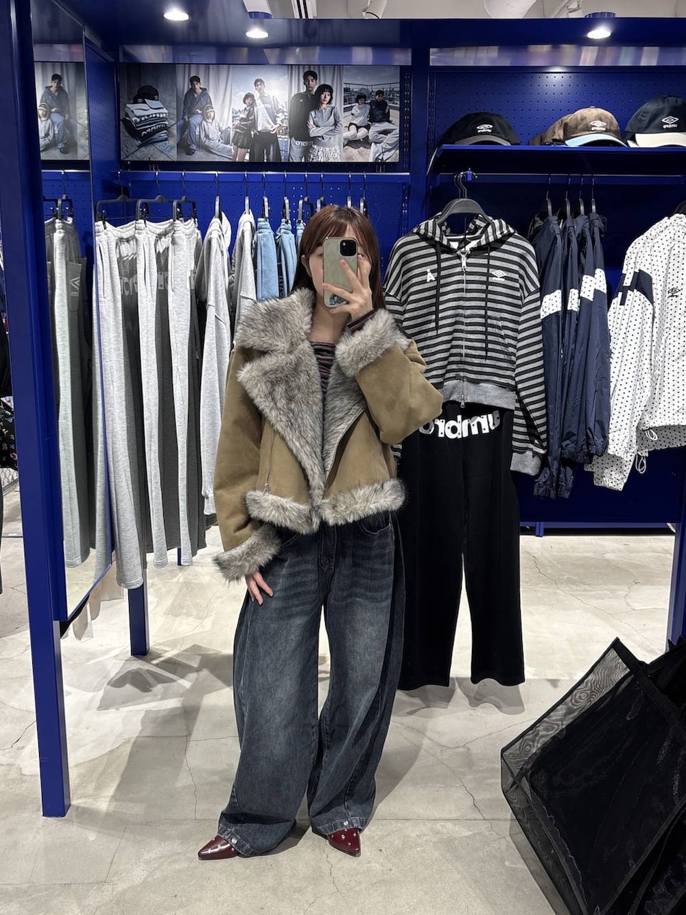 レッド系のTシャツ/カットソー、ブルー系のデニムパンツ、グレー系のムートンコートを着用したレディースの秋コーディネートの5枚目の写真