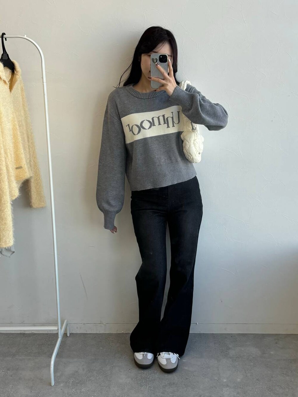 ホワイト系のショルダーバッグ、ブラック系のデニムパンツ、グレー系のニット/セーターを着用したレディースの冬コーディネートの5枚目の写真