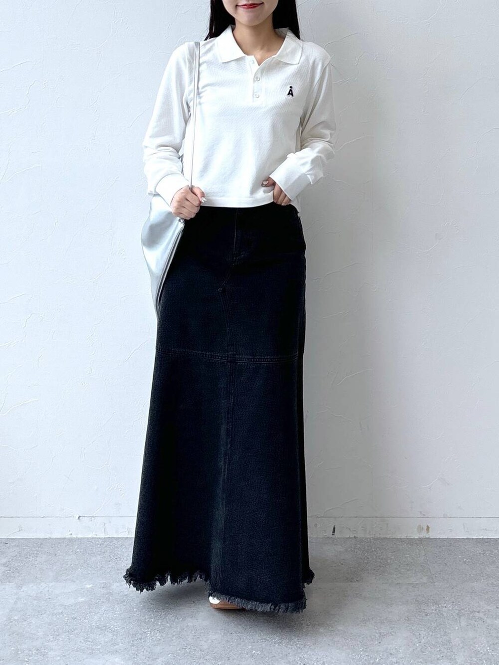 ブラック系のデニムスカート、グレー系のバックパック/リュック、ホワイト系のポロシャツを着用したレディースの秋コーディネートの2枚目の写真