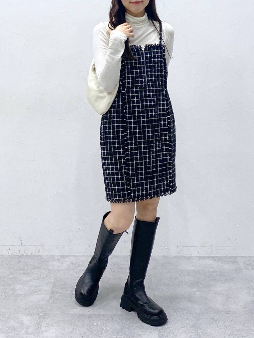 ブラック系のブーツ、ベージュ系のTシャツ/カットソー、ブラック系のワンピースを着用したレディースの冬コーディネートの2枚目の写真