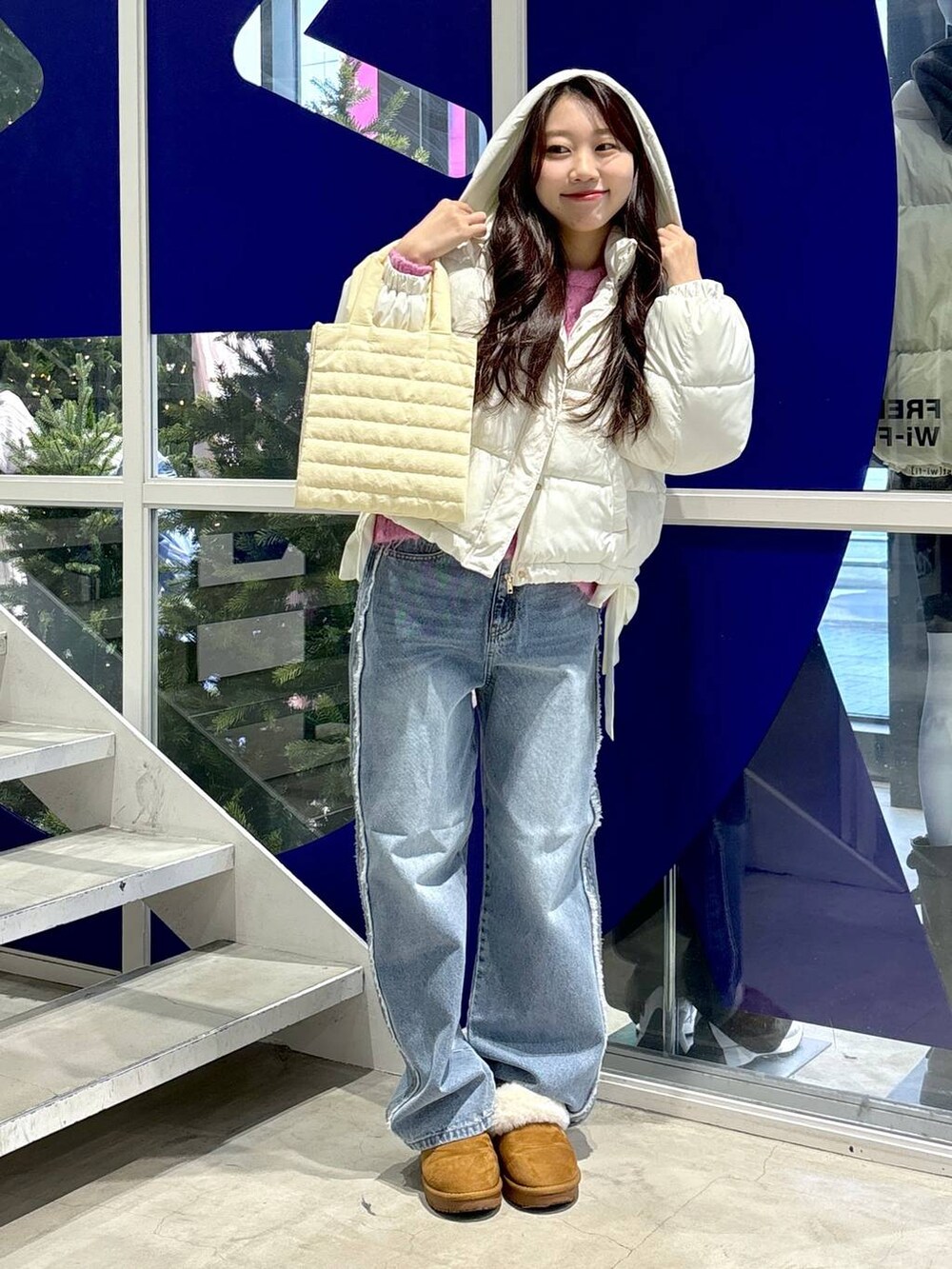 ホワイト系のダウンジャケット/コート、ピンク系のニット/セーター、ブルー系のデニムパンツを着用したレディースの秋コーディネートの3枚目の写真