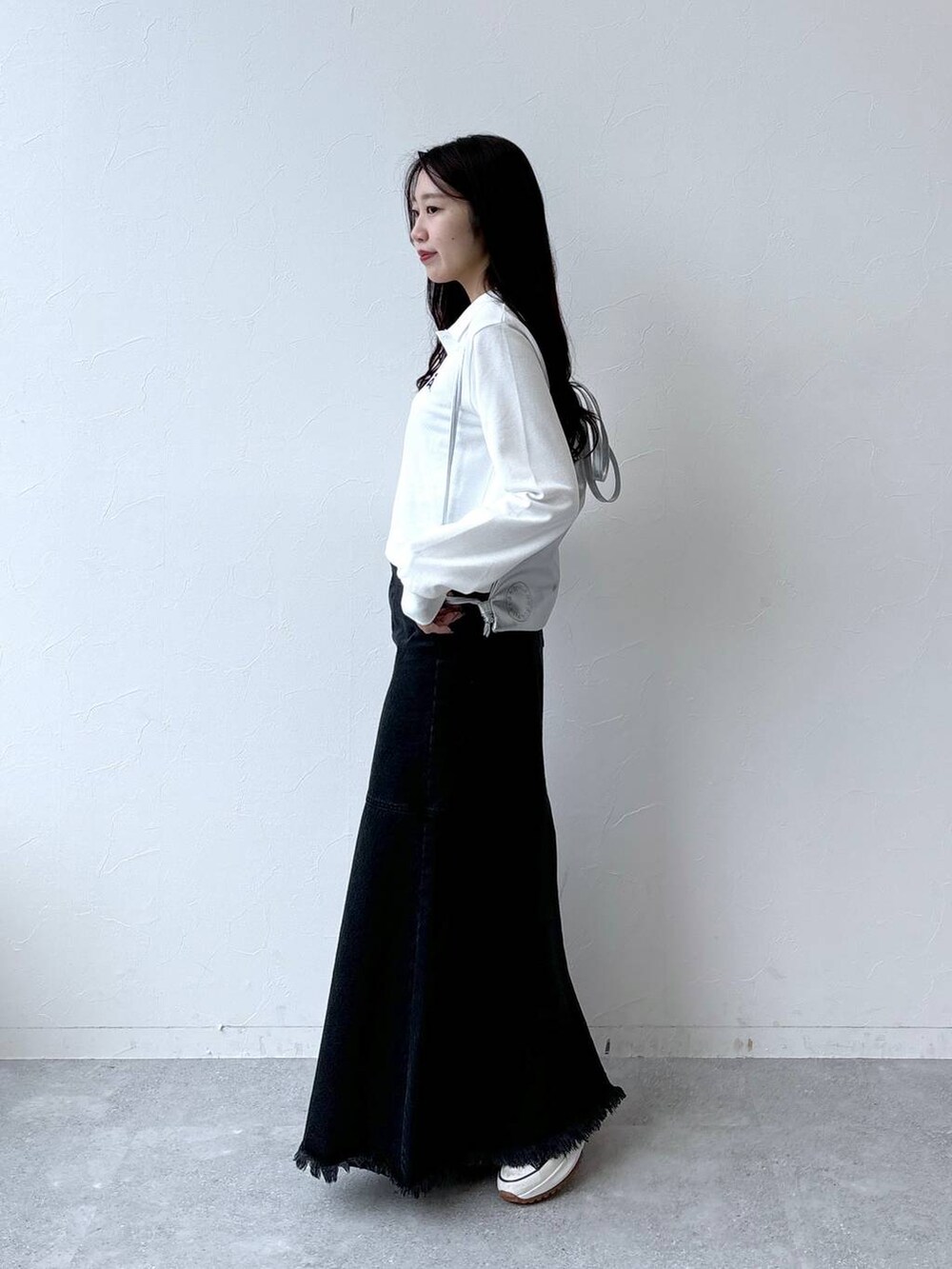 ブラック系のデニムスカート、グレー系のバックパック/リュック、ホワイト系のポロシャツを着用したレディースの秋コーディネートの3枚目の写真