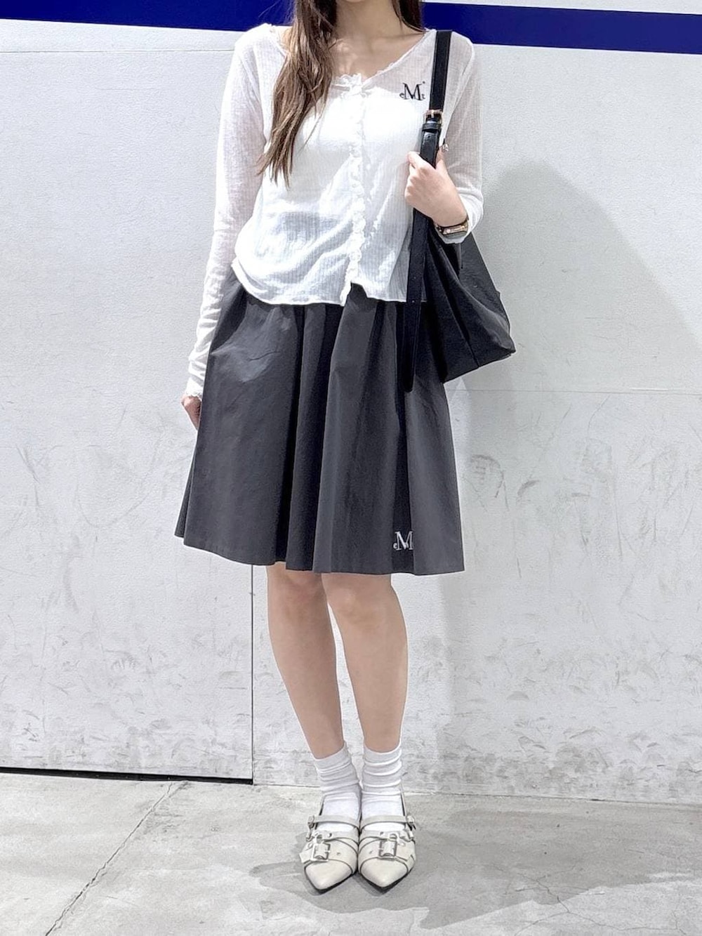 ホワイト系のパンプス、ブラック系のショルダーバッグ、グレー系のスカートを着用したレディースの春コーディネートの2枚目の写真