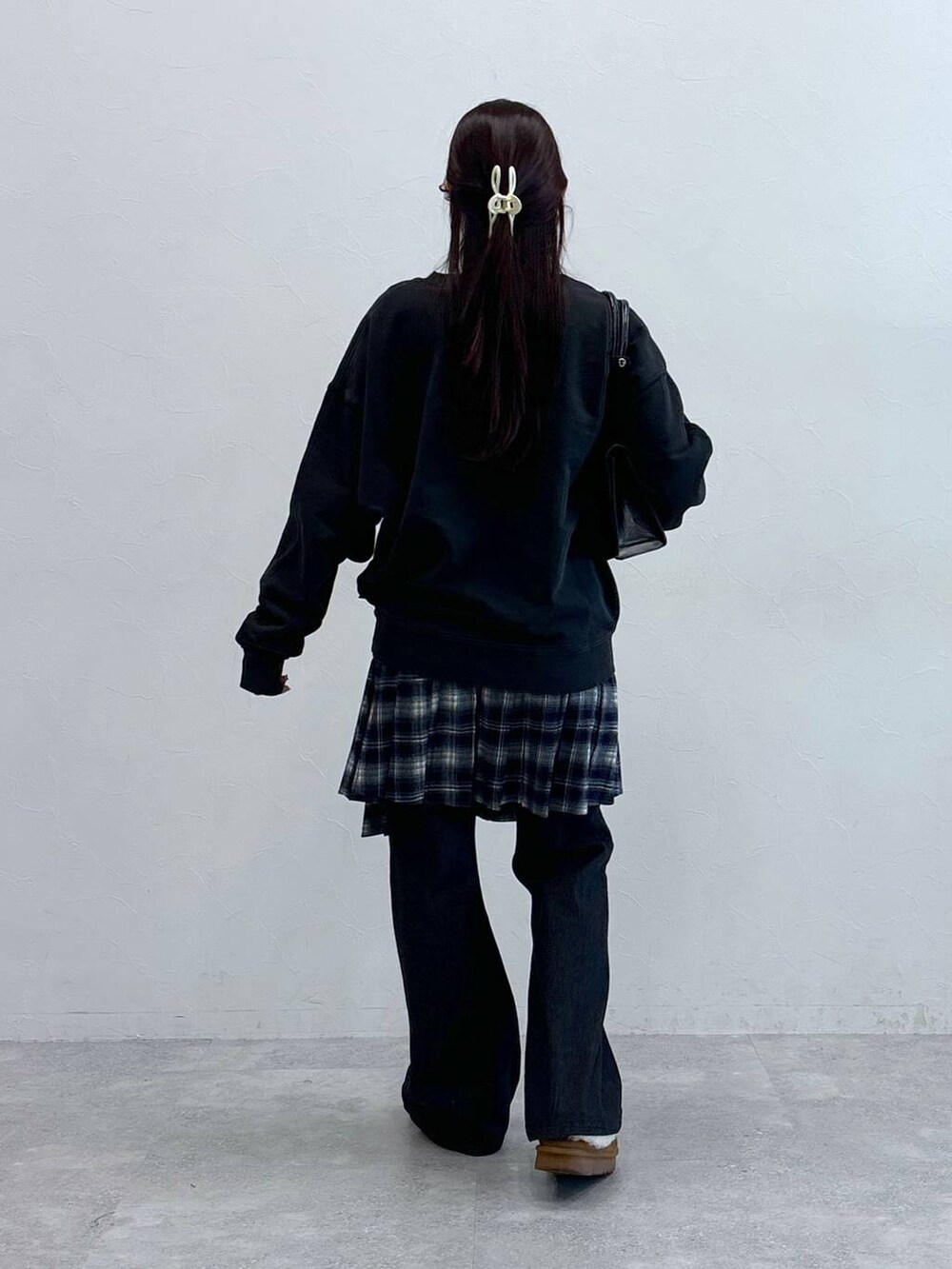 ブラック系のデニムパンツ、ブラック系のハンドバッグ、ブルー系のスカートを着用したレディースの冬コーディネートの5枚目の写真