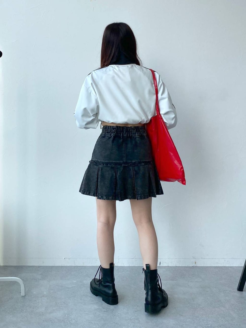 ホワイト系のブルゾン、レッド系のトートバッグ、ブラック系のデニムスカートを着用したレディースの春コーディネートの4枚目の写真