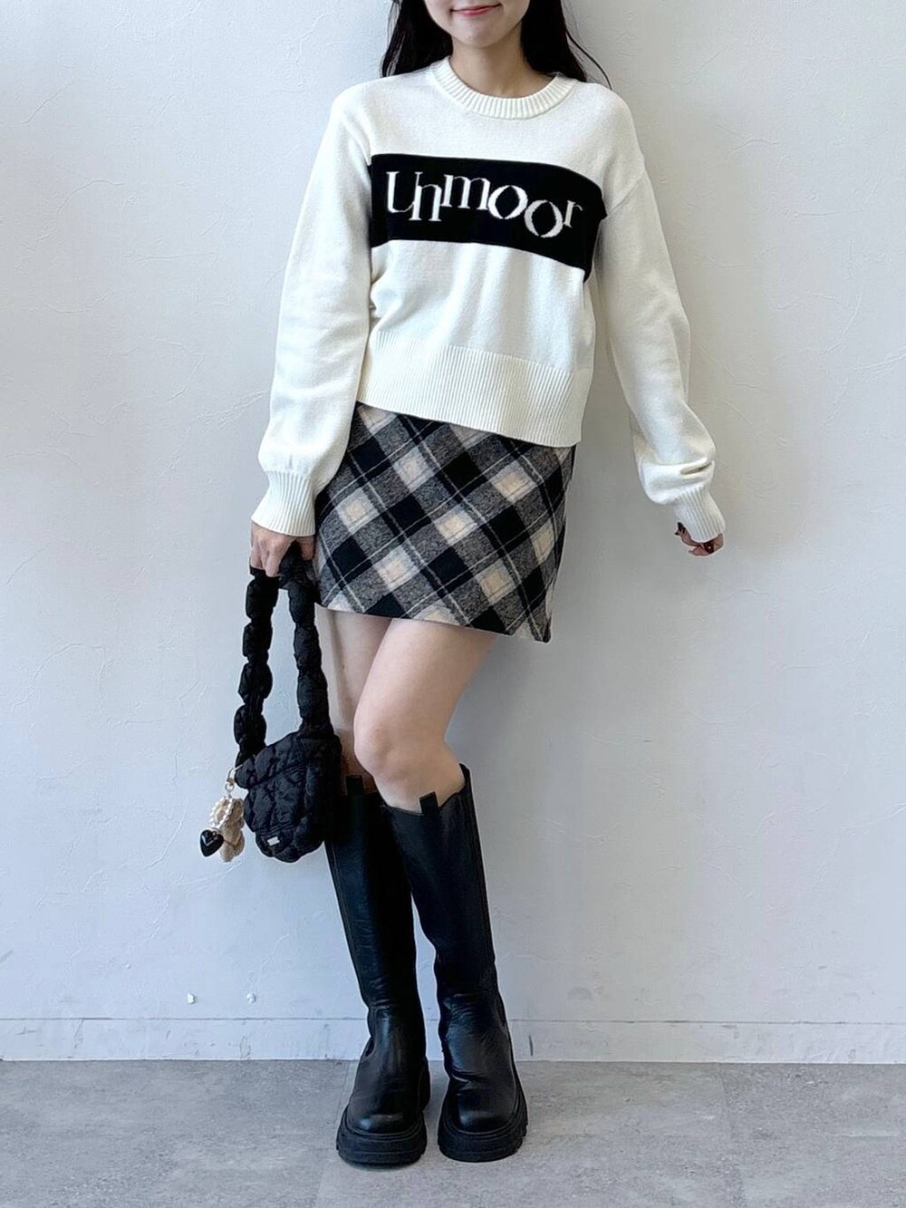 ブラック系のショルダーバッグ、ブラック系のスカート、ブラック系のブーツを着用したレディースの冬コーディネートの2枚目の写真