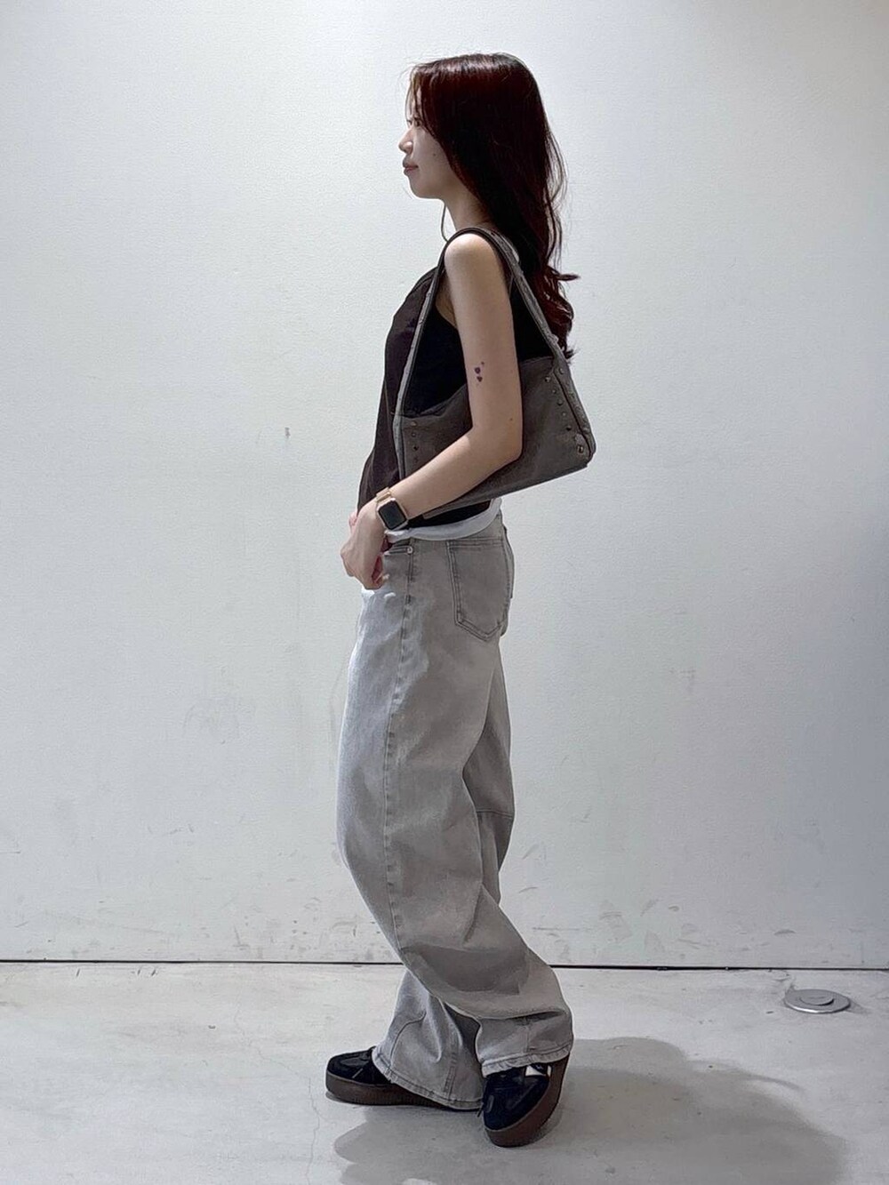 グレー系のデニムパンツ、ブラウン系のタンクトップ、グレー系のハンドバッグを着用したレディースの夏コーディネートの3枚目の写真