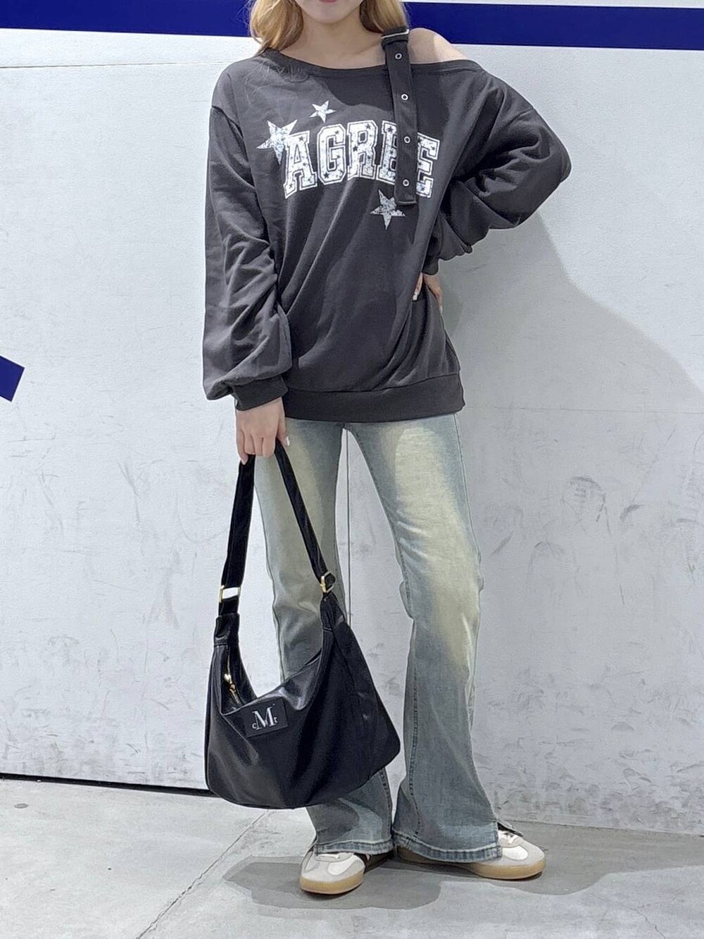 グレー系のスウェット、ブラック系のトートバッグ、ブルー系のデニムパンツを着用したレディースの秋コーディネートの2枚目の写真