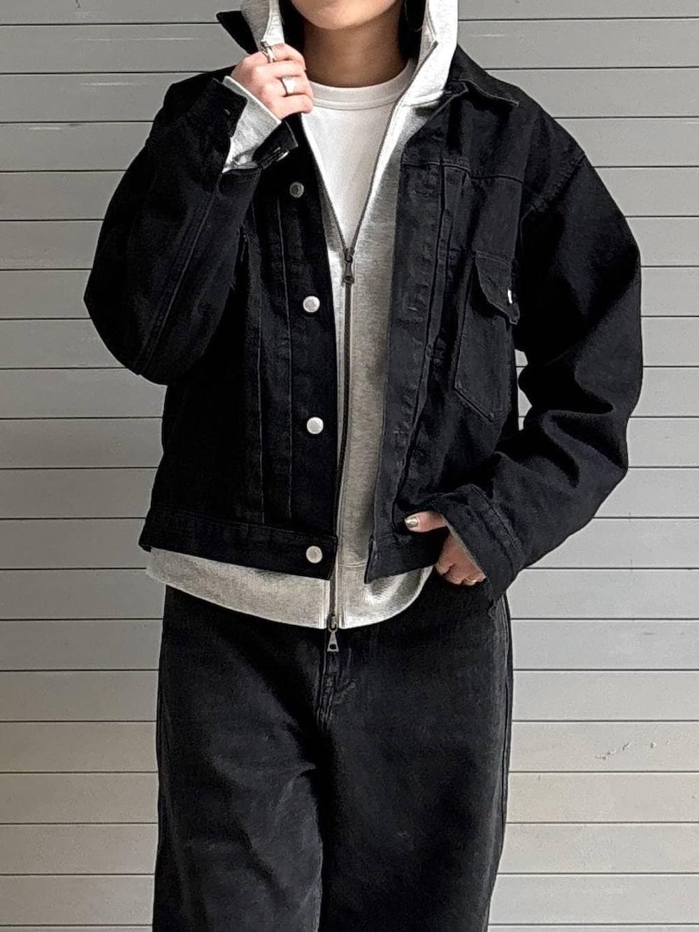 ブラック系のデニムパンツ、ブラック系のデニムジャケット、グレー系のパーカーを着用したレディースの冬コーディネートの5枚目の写真