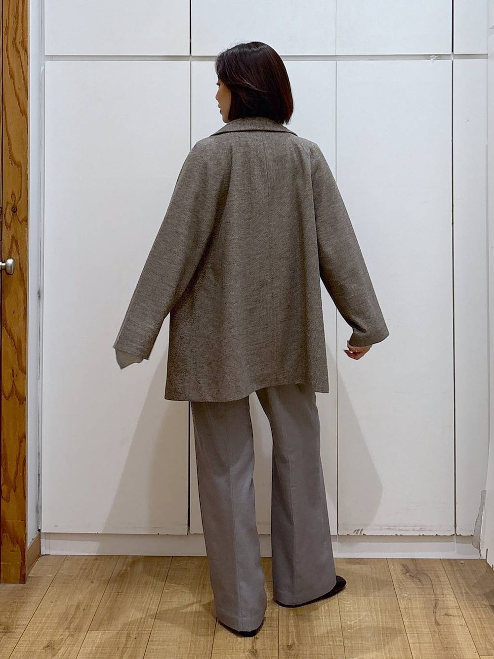 ブラウン系のチェスターコート、グレー系のその他パンツ、ホワイト系のTシャツ/カットソーを着用したレディースの秋コーディネートの4枚目の写真