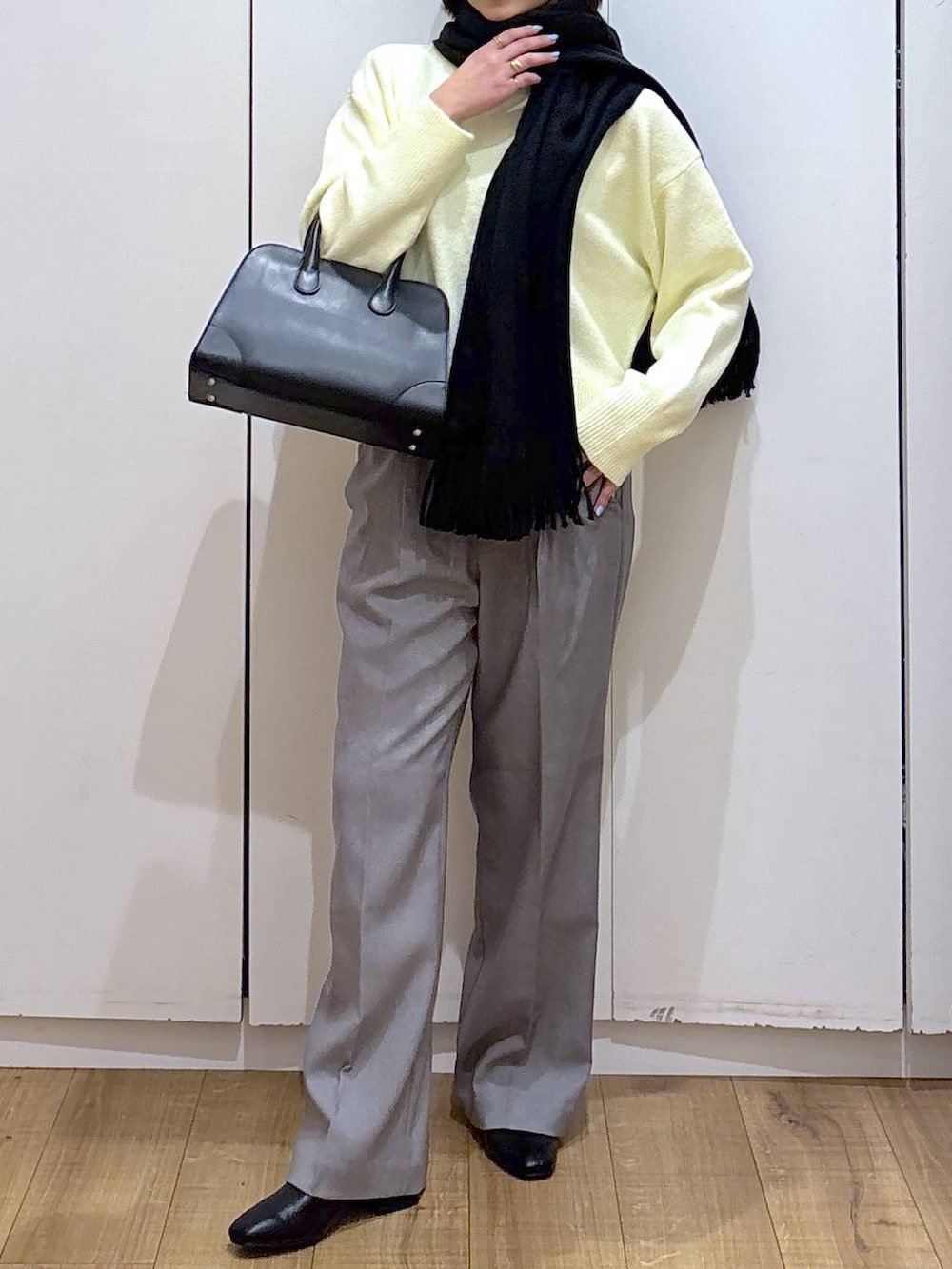 イエロー系のニット/セーター、グレー系のその他パンツ、ブラック系のショルダーバッグを着用したレディースの冬コーディネートの2枚目の写真