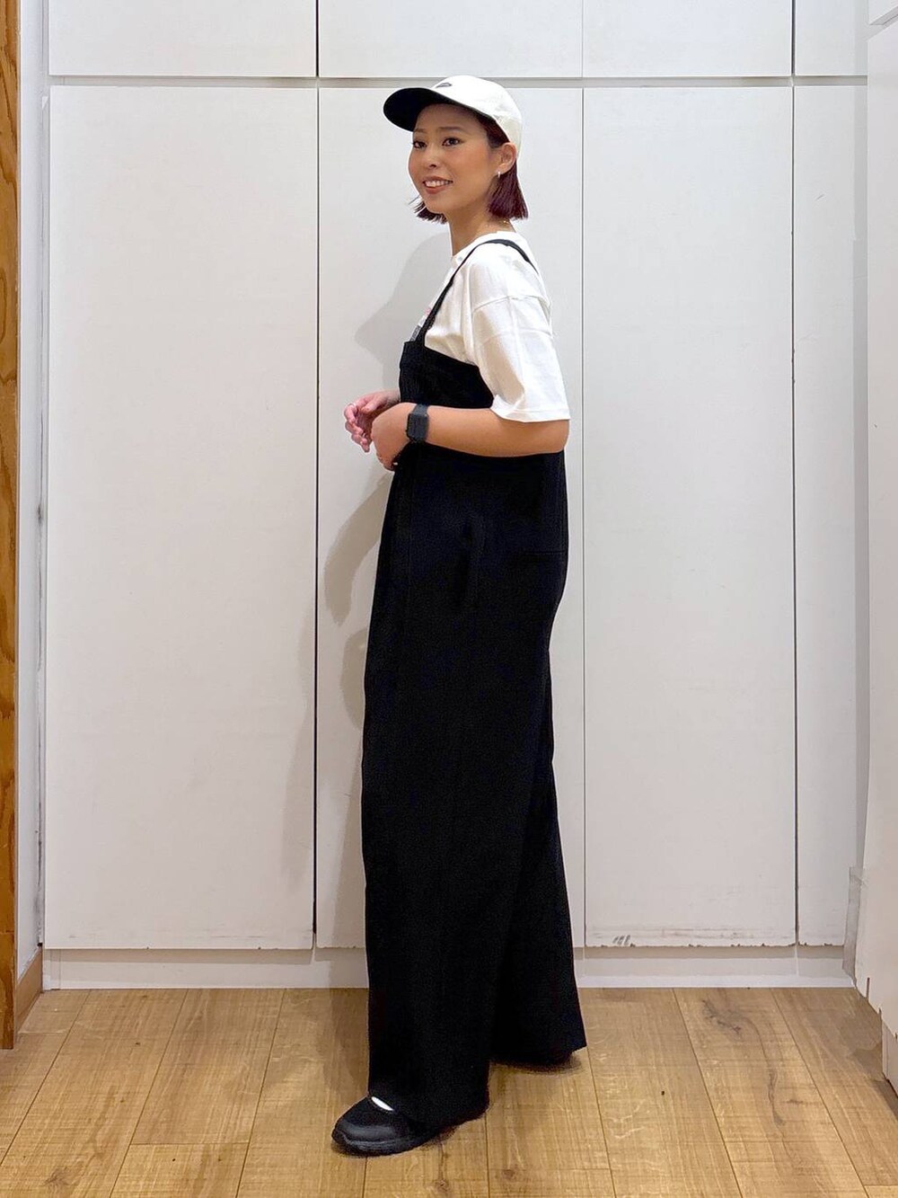 ブラック系のスニーカー、ホワイト系のTシャツ/カットソー、ブラック系のつなぎ/オールインワンを着用したレディースの春コーディネートの4枚目の写真