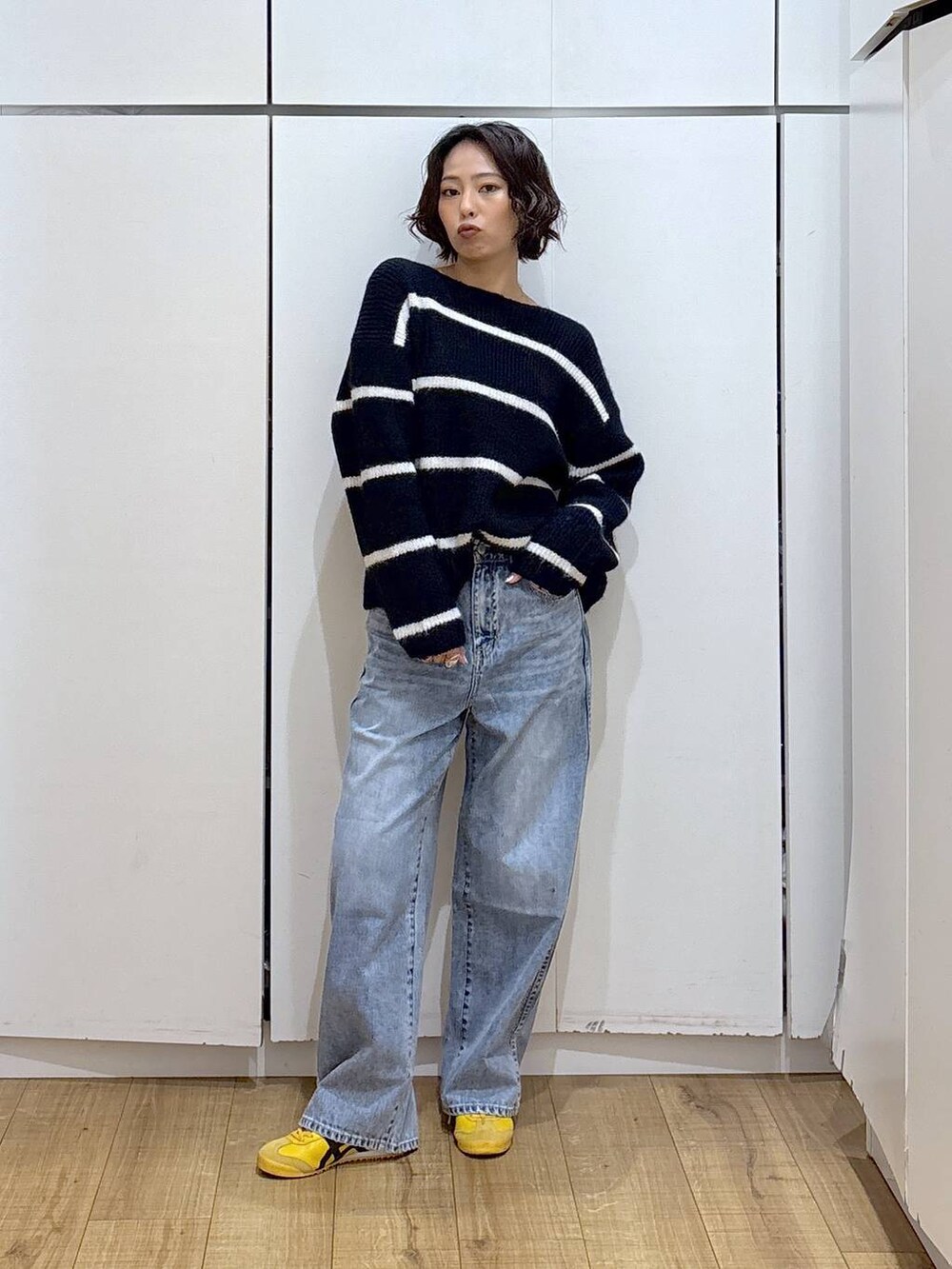 ブルー系のデニムパンツ、ブルー系のニット/セーター、ゴールド系のピアス(両耳用)を着用したレディースの冬コーディネートの2枚目の写真