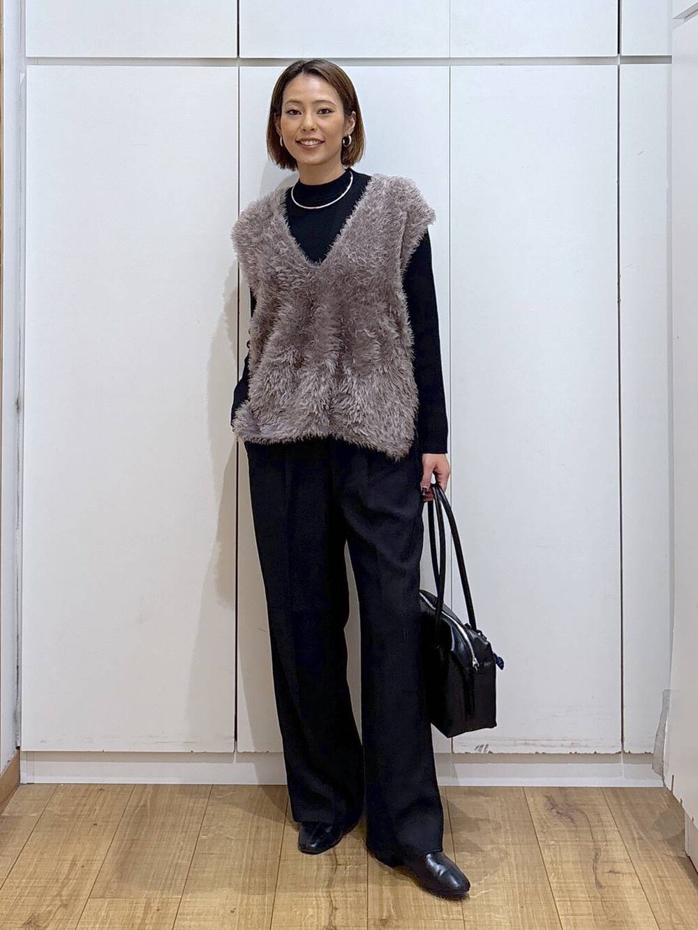 ブラック系のボストンバッグ、ブラック系のニット/セーター、ブラック系のその他パンツを着用したレディースの秋コーディネートの2枚目の写真