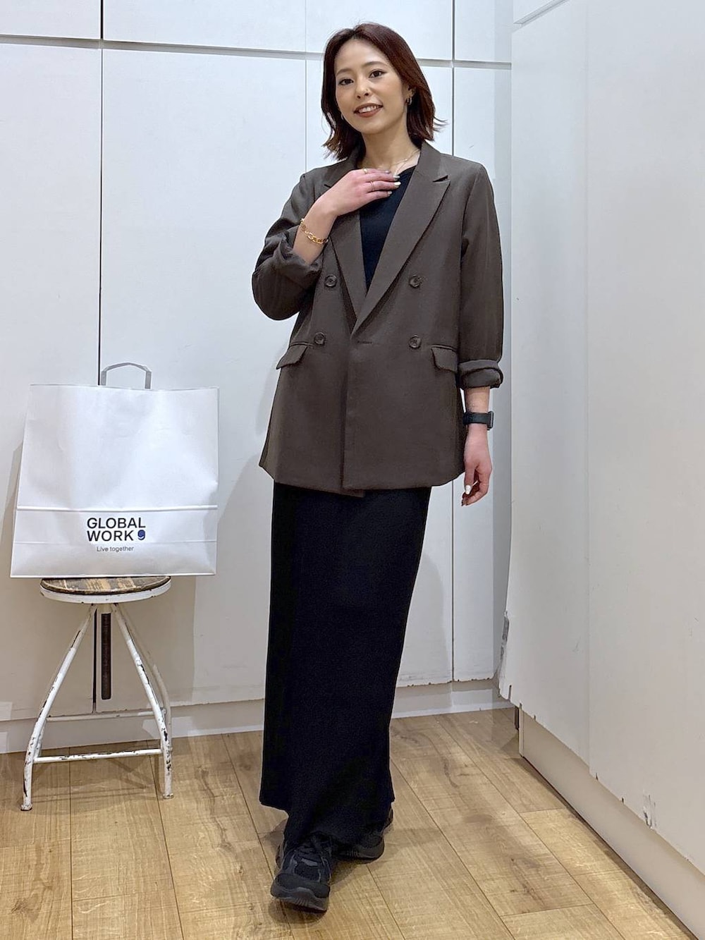 ブラウン系のテーラードジャケット、ブラック系のスカート、ゴールド系のネックレスを着用したレディースの春コーディネートの2枚目の写真