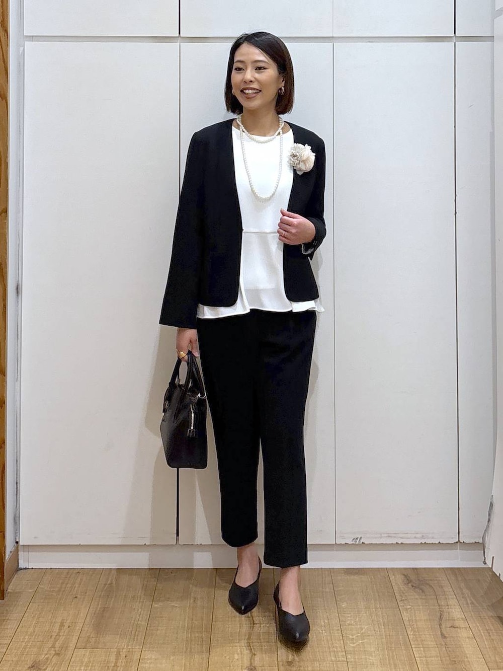 ブラック系のショルダーバッグ、ブラック系のパンプス、ブラック系のセットアップを着用したレディースの冬コーディネートの4枚目の写真