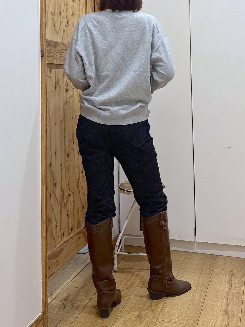 ブラック系のデニムパンツ、ブラウン系のブーツ、グレー系のニット/セーターを着用したレディースの秋コーディネートの6枚目の写真