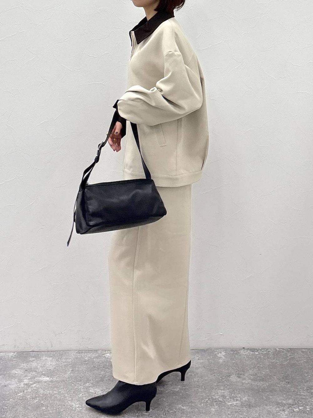 ブラック系のブーツ、ブラック系のショルダーバッグ、ベージュ系のスカートを着用したレディースの冬コーディネートの4枚目の写真