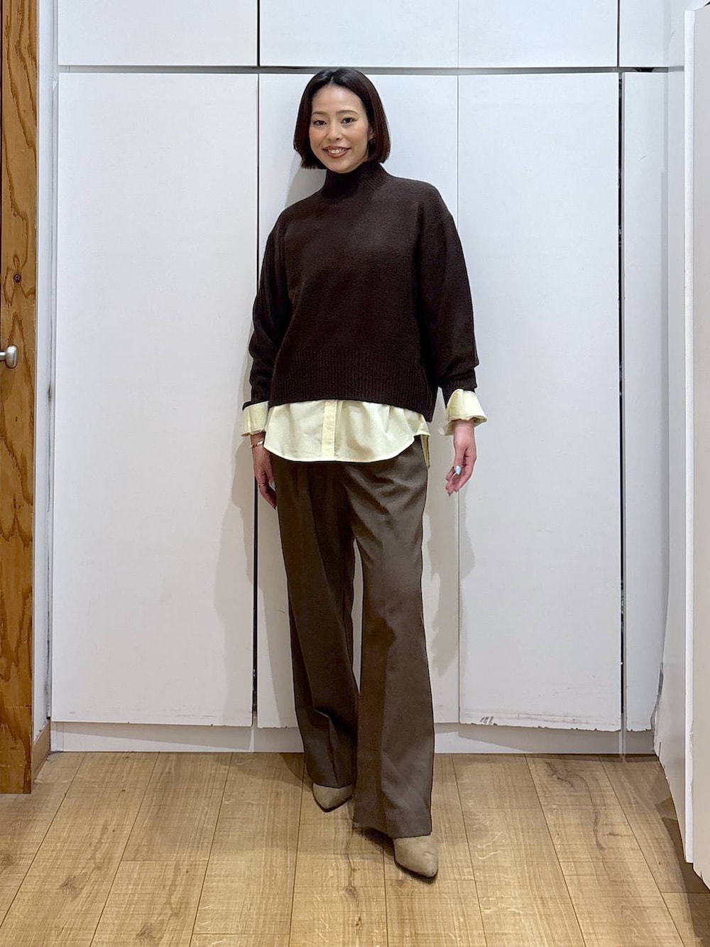 イエロー系のシャツ/ブラウス、ブラウン系のニット/セーター、ブラウン系のその他パンツを着用したレディースの冬コーディネートの2枚目の写真