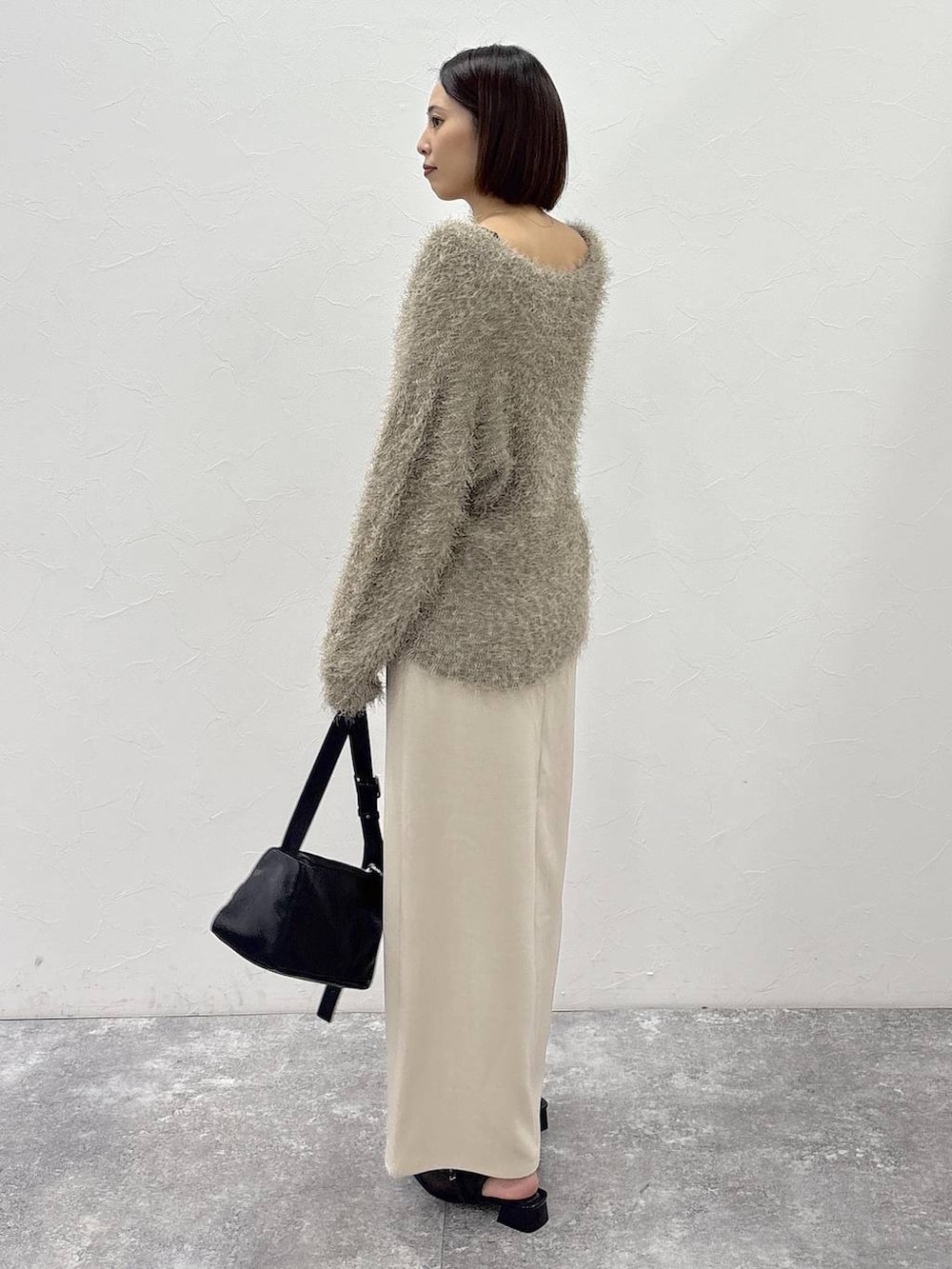 ブラック系のショルダーバッグ、ベージュ系のスカート、ゴールド系のピアス(両耳用)を着用したレディースの冬コーディネートの8枚目の写真