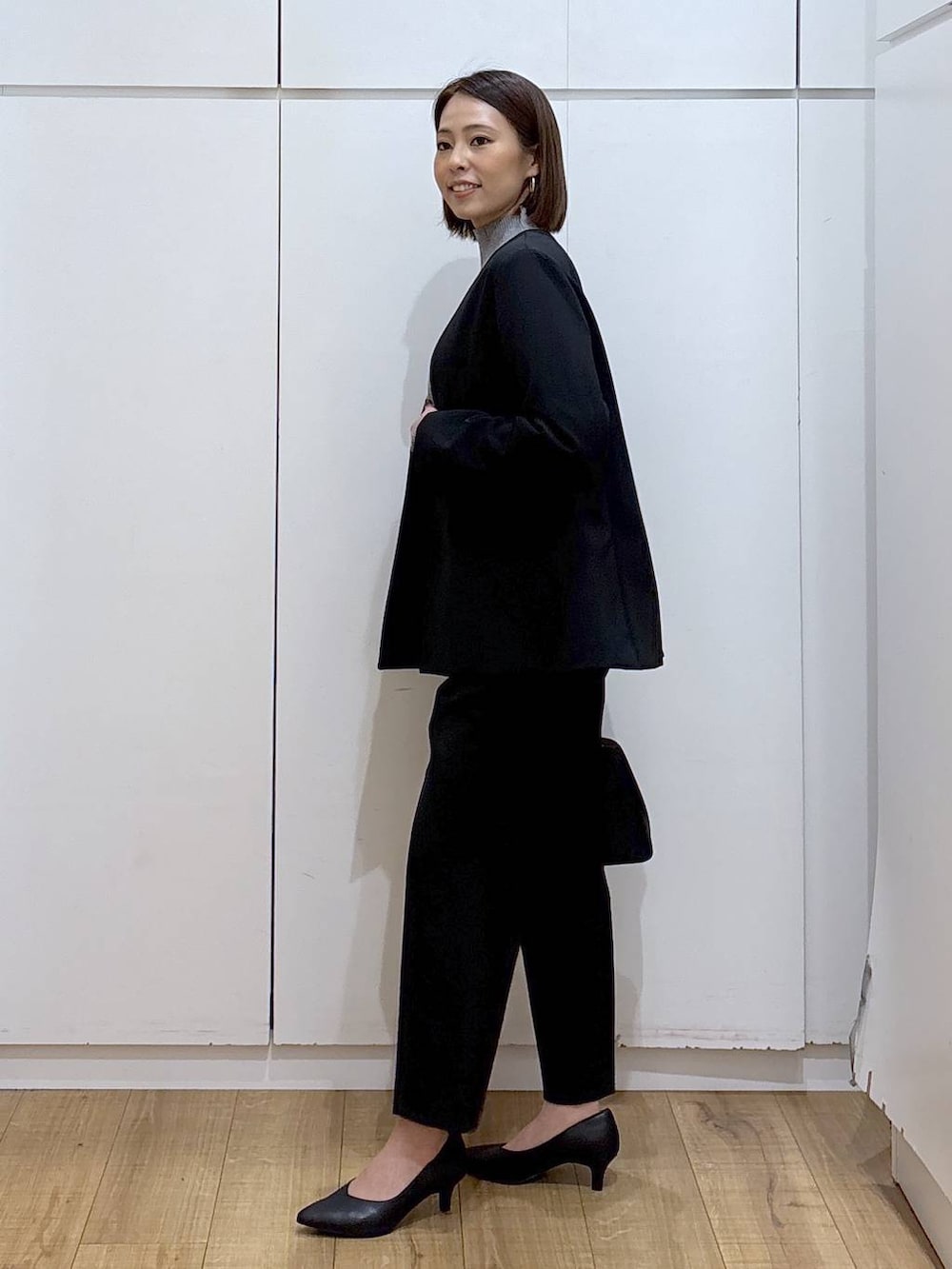 ブラック系のショルダーバッグ、ブラック系のパンプス、グレー系のニット/セーターを着用したレディースの冬コーディネートの5枚目の写真