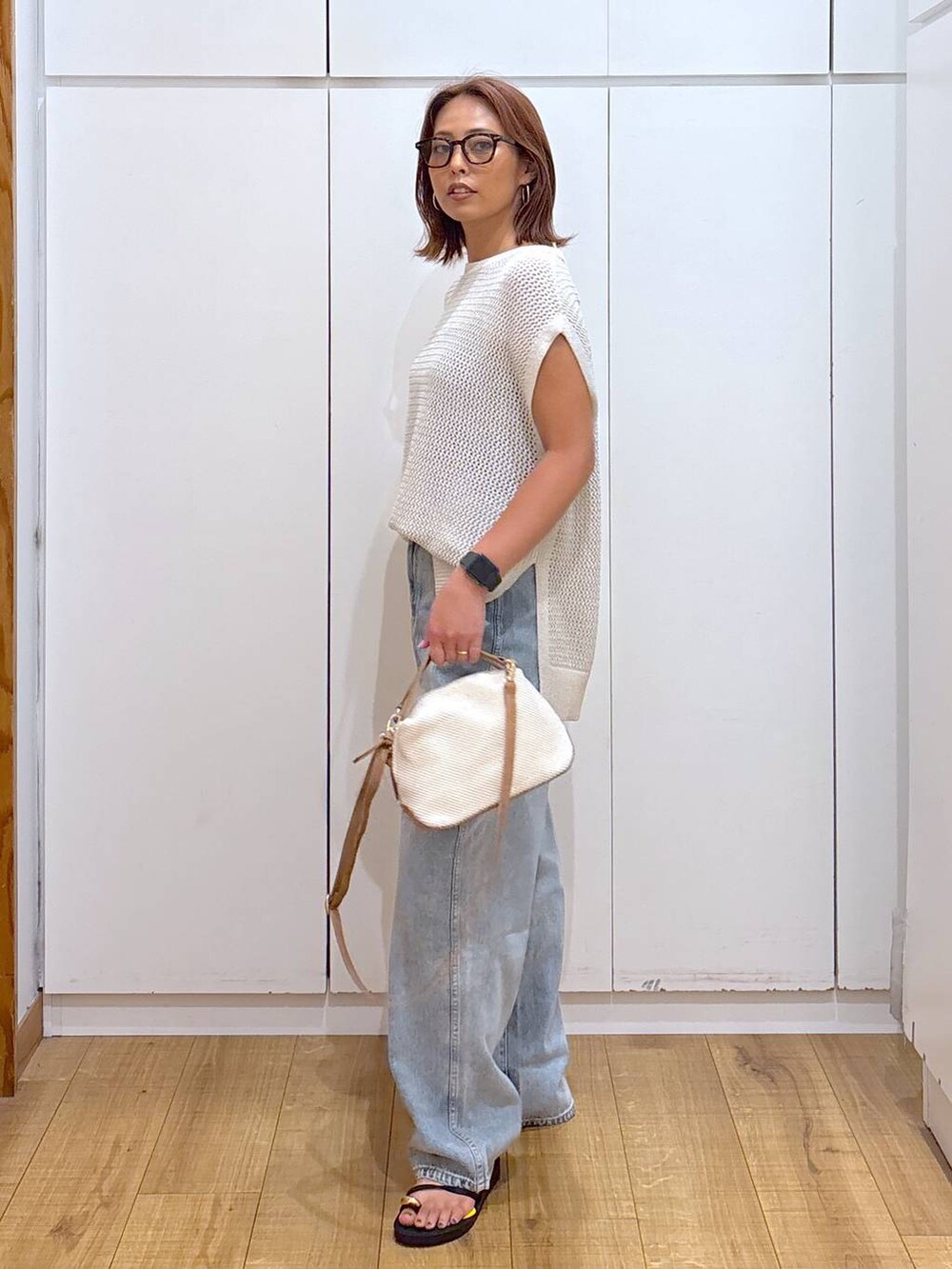 ブルー系のデニムパンツ、ホワイト系のショルダーバッグ、ブラック系のキャミソールを着用したレディースの夏コーディネートの4枚目の写真