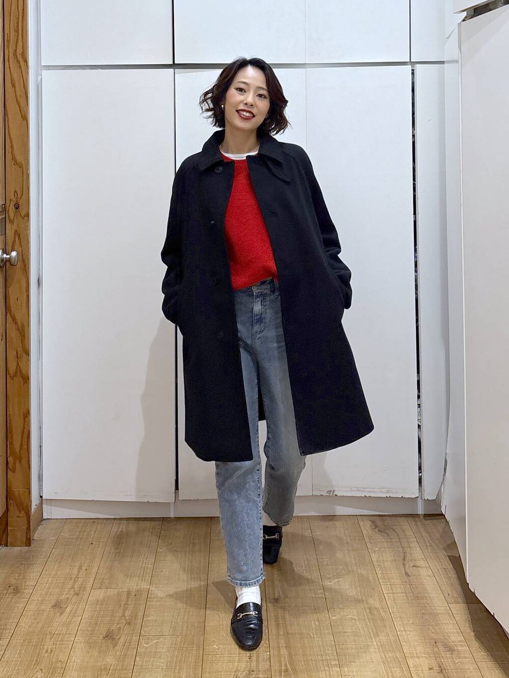 ブラック系のローファー、ブラック系のステンカラーコート、ブルー系のデニムパンツを着用したレディースの冬コーディネートの6枚目の写真