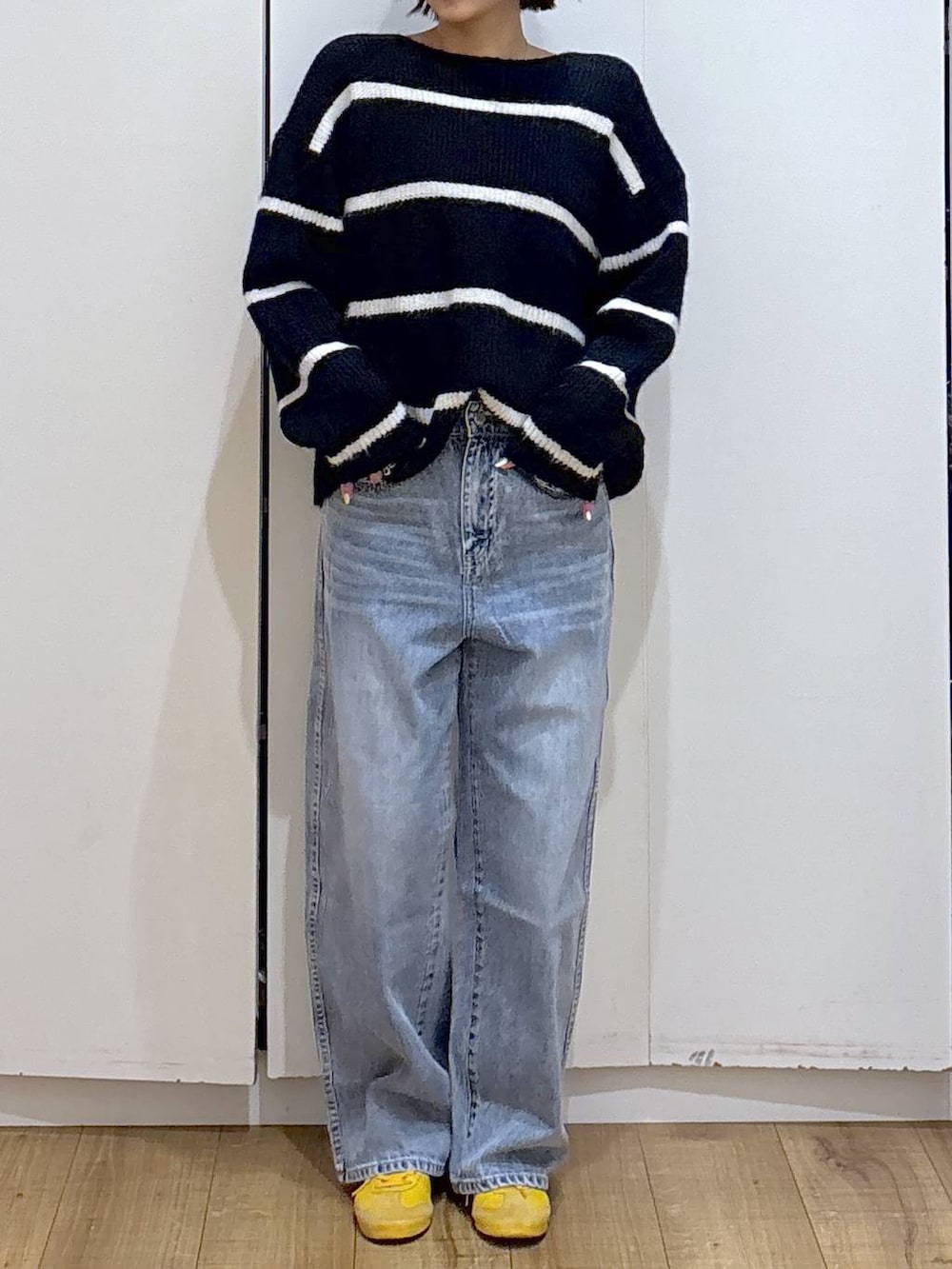 ブルー系のデニムパンツ、ブルー系のニット/セーター、ゴールド系のピアス(両耳用)を着用したレディースの冬コーディネートの3枚目の写真