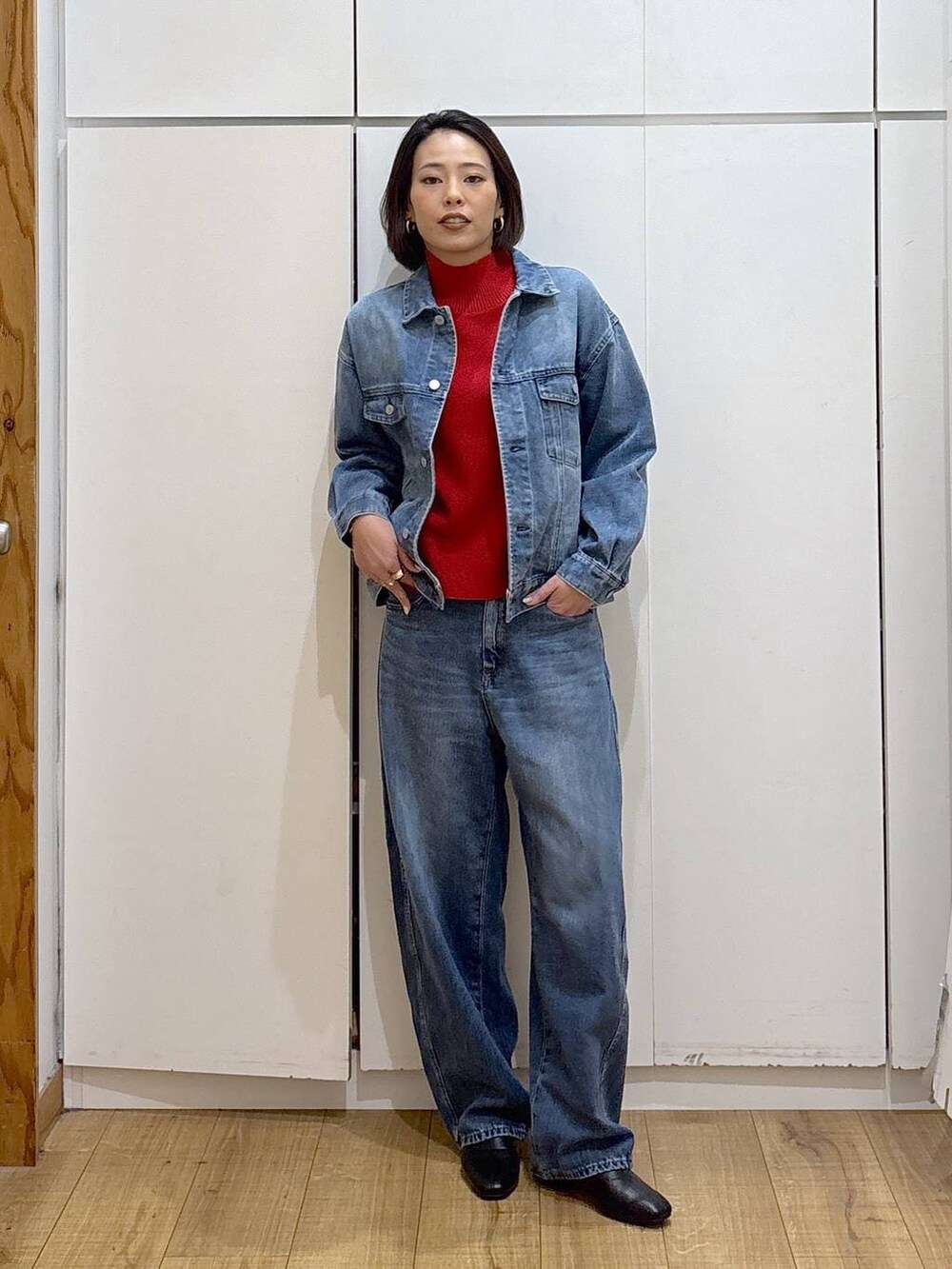 レッド系のニット/セーター、ブラック系のブーツ、ブルー系のデニムジャケットを着用したレディースの冬コーディネートの2枚目の写真