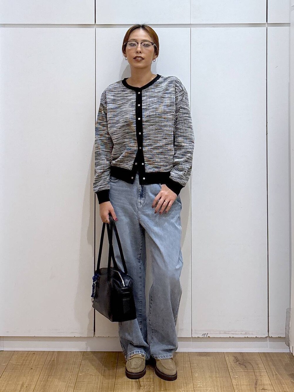 ブラック系のボストンバッグ、ブルー系のデニムパンツ、ベージュ系のローファーを着用したレディースの秋コーディネートの2枚目の写真