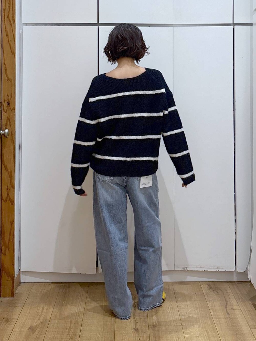 ブルー系のデニムパンツ、ブルー系のニット/セーター、ゴールド系のピアス(両耳用)を着用したレディースの冬コーディネートの7枚目の写真