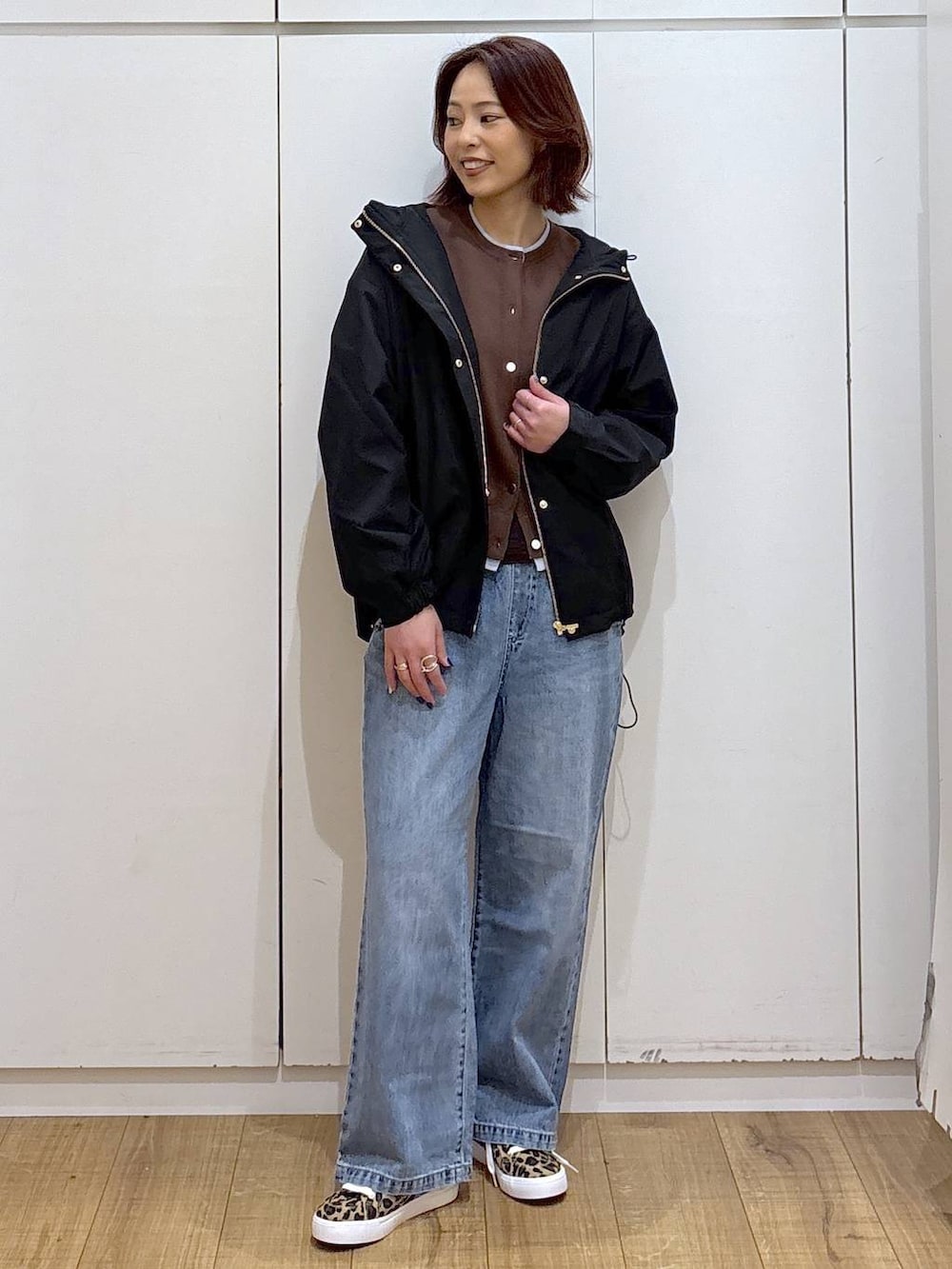 ブルー系のデニムパンツ、ブラック系のマウンテンパーカー、ブラウン系のカーディガン/ボレロを着用したレディースの春コーディネートの3枚目の写真