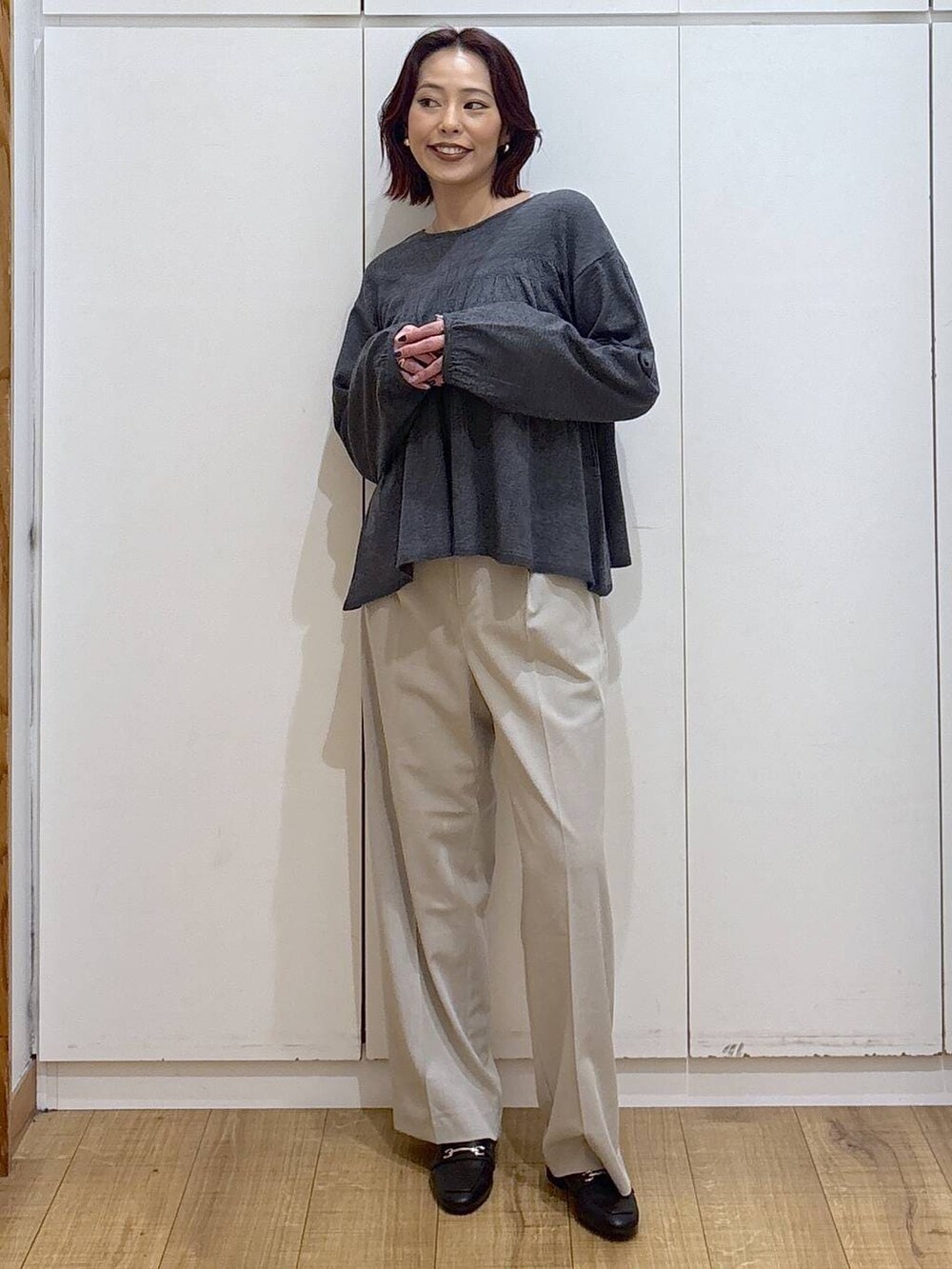 ブラック系のローファー、ベージュ系のスラックス、グレー系のカーディガン/ボレロを着用したレディースの春コーディネートの2枚目の写真