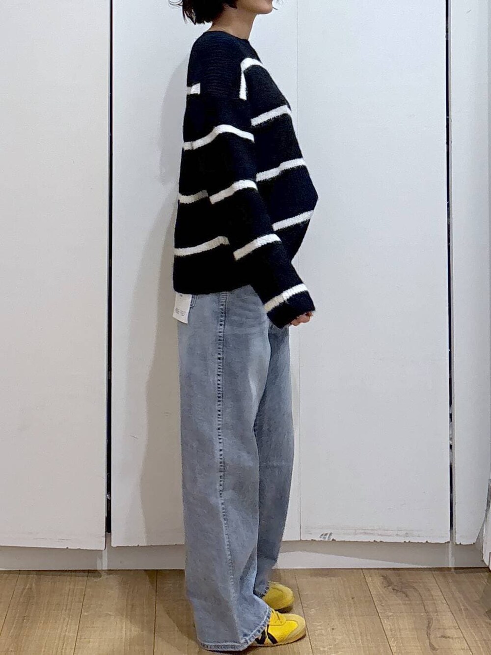 ブルー系のデニムパンツ、ブルー系のニット/セーター、ゴールド系のピアス(両耳用)を着用したレディースの冬コーディネートの8枚目の写真