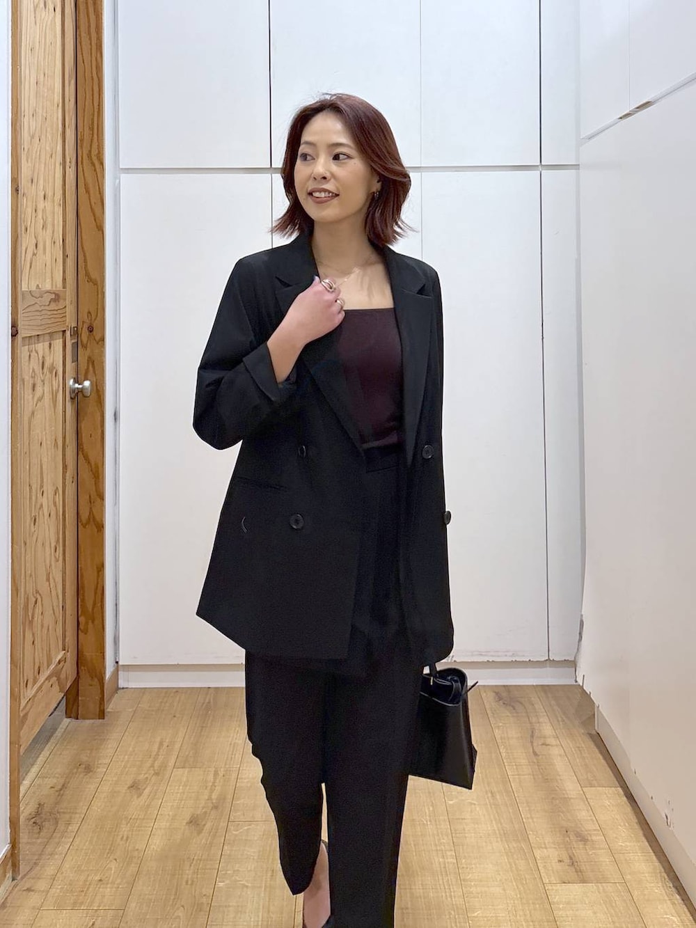 ブラック系のパンプス、ブラック系のスラックス、ブラック系のテーラードジャケットを着用したレディースの春コーディネートの6枚目の写真