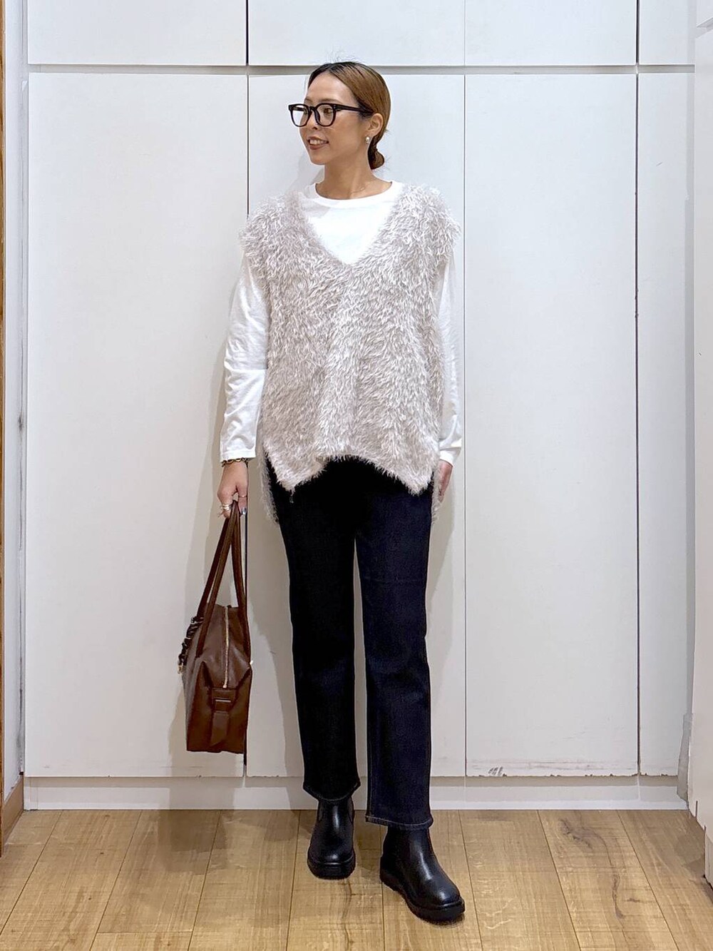 ブラウン系のボストンバッグ、ブルー系のデニムパンツ、ホワイト系のTシャツ/カットソーを着用したレディースの秋コーディネートの2枚目の写真