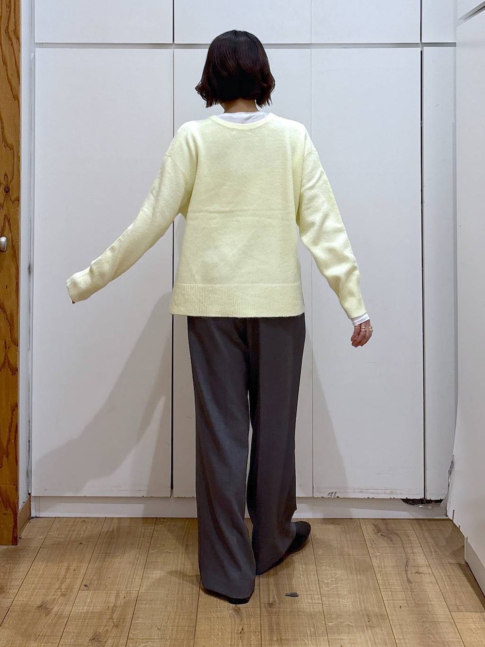 イエロー系のニット/セーター、ブラック系のブーツ、ゴールド系のピアス（両耳用）を着用したレディースの冬コーディネートの5枚目の写真