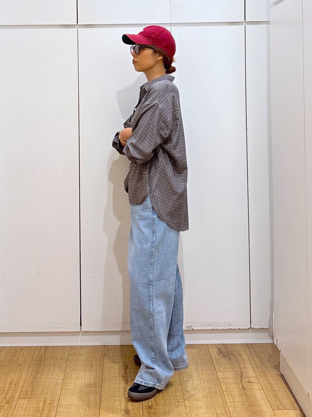 ブラック系のスニーカー、ホワイト系のキャミソール、ブルー系のデニムパンツを着用したレディースの秋コーディネートの3枚目の写真