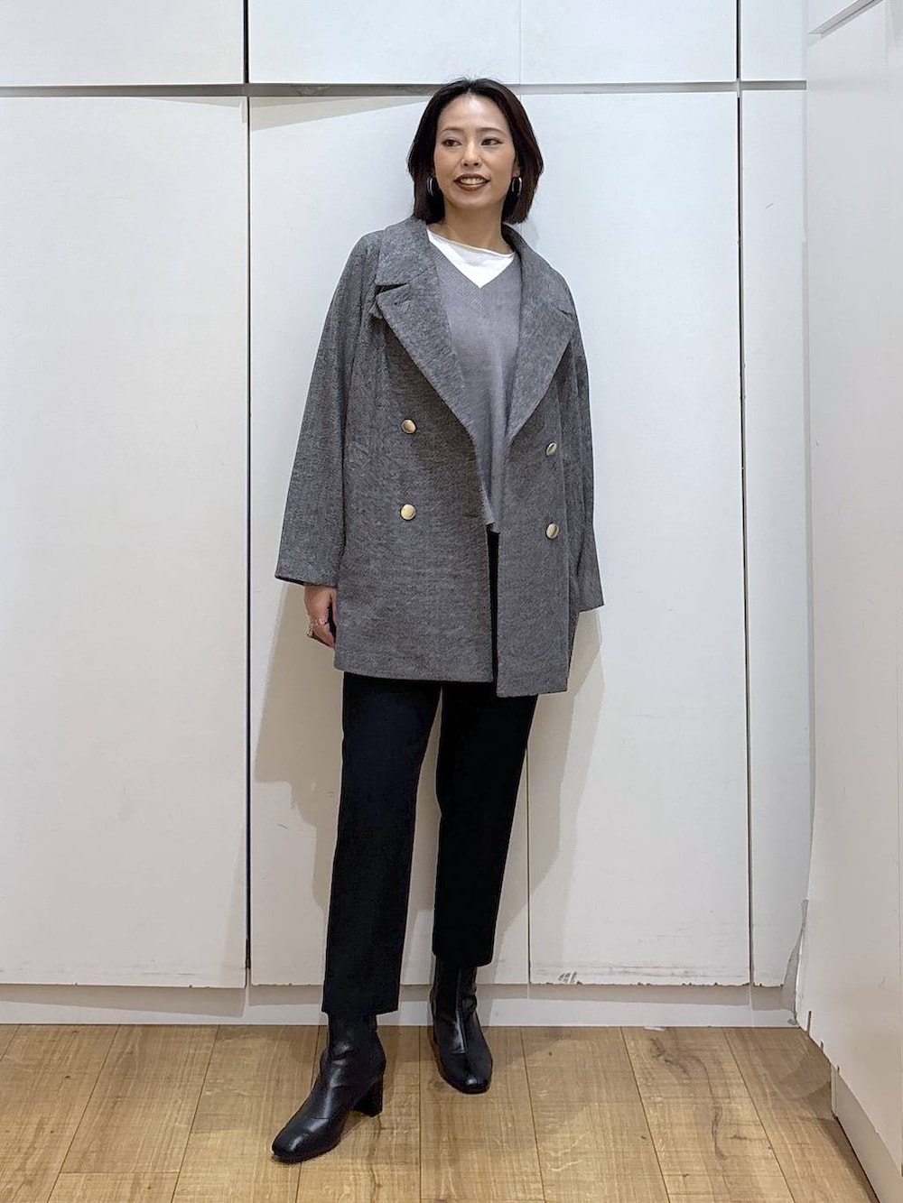 グレー系のチェスターコート、ブラック系のその他パンツ、グレー系のニット/セーターを着用したレディースの秋コーディネートの2枚目の写真